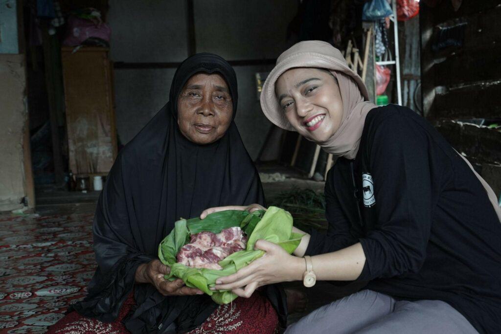 Chiki memberikan daging kurban kepada Zambiah (70), warga Dusun 1 Desa Jaring Halus.