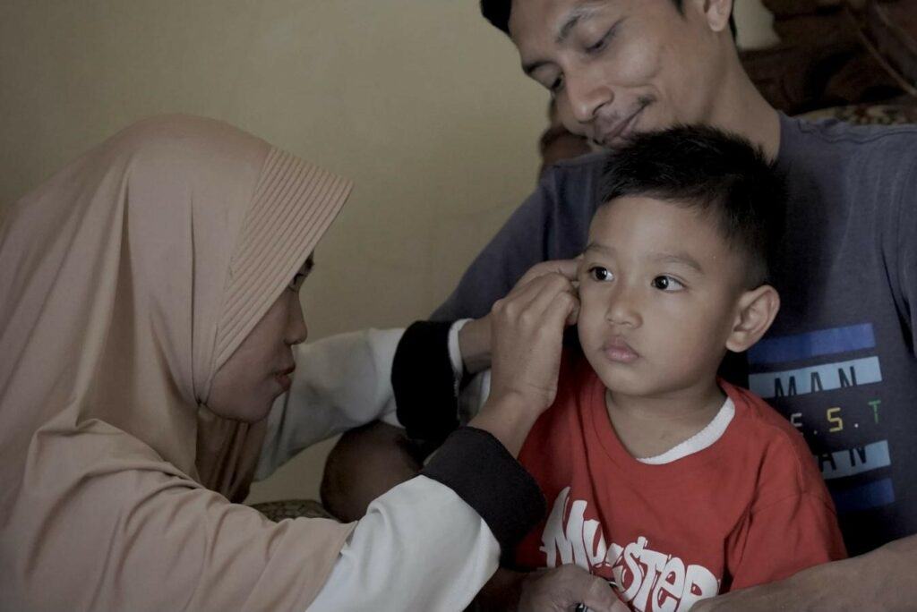 bantuan alat dengar2 dompet dhuafa Kedua orang tua, Ana (kiri) bersama Jauhar (kanan) memasangkan Alat Bantu Dengar (ABD) pada Yazdan, sang ananda (tengah).