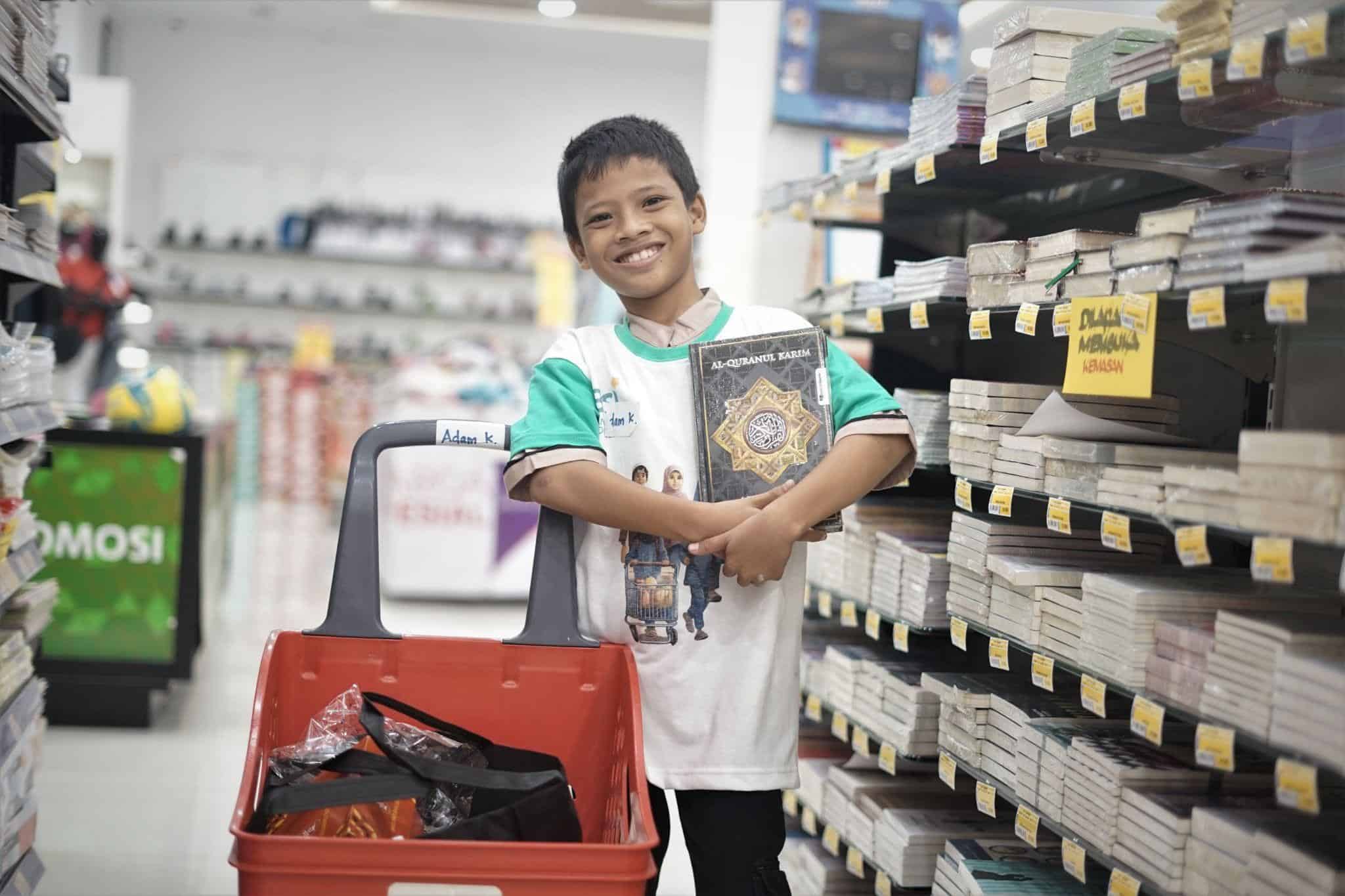 belanja bareng yatim1 dompet dhuafa Adam sedang tersenyum lebar karena ia bisa memberi Al-Qur'an impiannya melalui Program Belanja Bareng Yatim yang diselenggarakan oleh BSI dan Dompet Dhuafa.