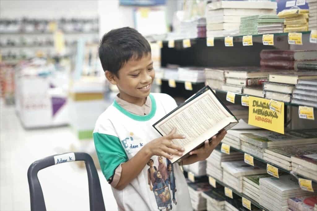belanja bareng yatim3 dompet dhuafa Adam tengah memeriksa tiap halaman dari Al-Quran yang akan dibelinya.
