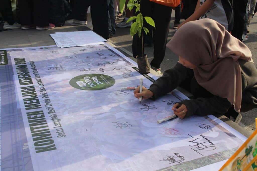 Para peserta aksi menandatangani komitmen menjaga kebersihan bumi.