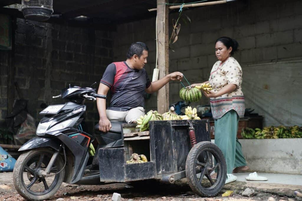 keluarga tangguh5 dompet dhuafa Dibantu sang istri, Kang Untung menaikkan puluhan sisir pisang ke atas motornya untuk didagangkan.