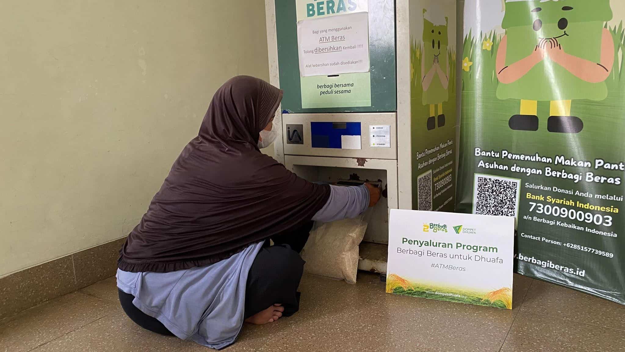 Seorang penerima manfaat berbagi beras sedang mengambil beras di ATM Beras Yayasan Hakimah Wa Rohmah.