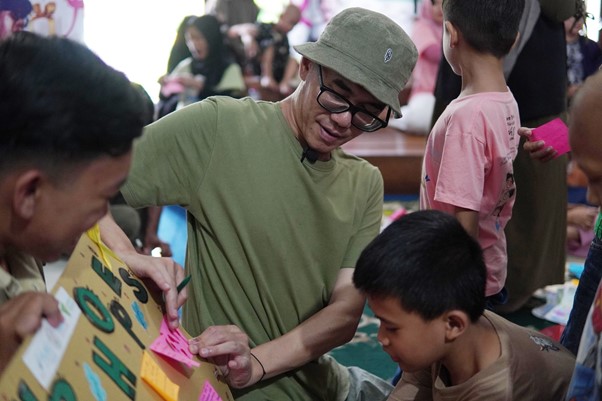 Panji Sakti membantu menempelkan kertas doa anak-anak penyintas kanker dalam kegiatan “Box of Happines” pada Jum’at (14/02/2025).