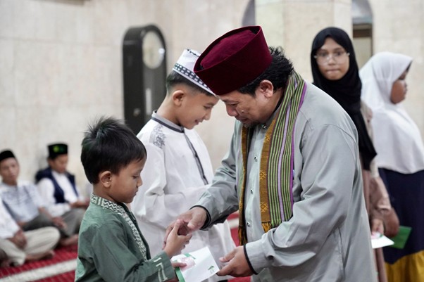 Ust. Ahmad Shonhaji selaku Direktur YSMI Dompet Dhuafa memberikan santunan kepada adik yatim dalam rangkaian Grebek Kampung Ramadan 1446 H di Masjid Al Hidayah Jalan Tanjung Sanyang RT 06/RW 08, Cawang, Jakarta Timur yang berlangsung pada Kamis (21/03/2025).