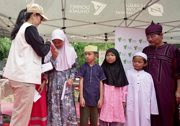 Marcella Zalianty (kiri) dan Bang Qubil (kanan), membagikan santunan kepada adik-adik yatim di Kampung Bambon, Jagakarsa, Jakarta Selatan, Sabtu (15/03/2025).