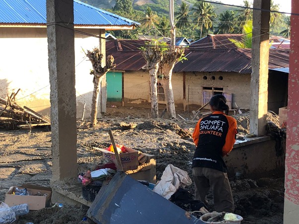 DMC Dompet Dhuafa membantu warga membersihkan puing-puing bangunan yang rusak akibat banjir.