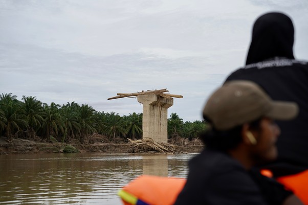 Tumpukan kayu sisa banjir bandang Sumatra di atas jembatan rusak di Sungai Tamiang.