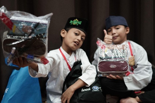 penerima manfaat remember 20262 dompet dhuafa Azka (kiri) dan Balfas (kanan) menunjukkan barang-barang yang diperolehnya dari kegiatan Remember 2026.
