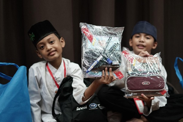 penerima manfaat remember 20263 dompet dhuafa Azka (kiri) dan Balfas (kanan) menunjukkan barang-barang yang diperolehnya dari kegiatan Remember 2026.