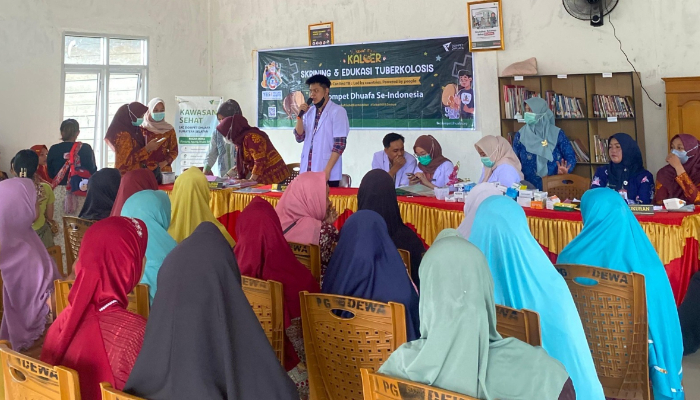 fotojet 2 dompet dhuafa Community health session on tuberculosis education: a man speaks at a podium while panelists sit at a long table, with many women in colorful hijabs listening in a hall.