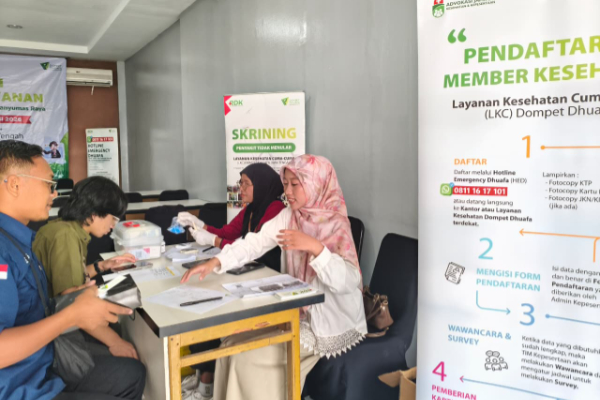 fotojet 5 dompet dhuafa Clinic registration desk where staff assist visitors with forms; banners advertising health services are visible in Indonesian.