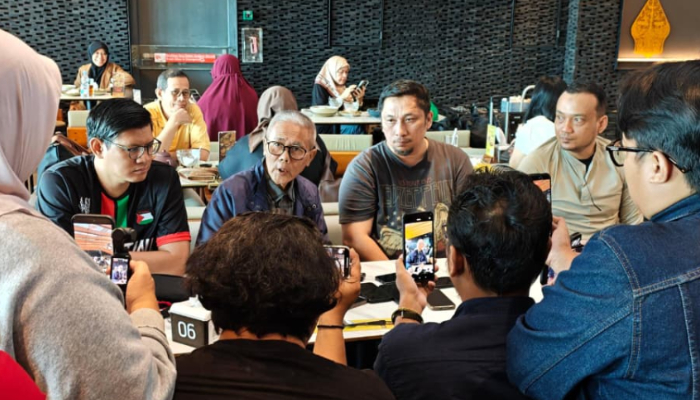 fotojet dompet dhuafa Group of diverse people around a cafe table, many holding up smartphones to take photos or record a discussion.