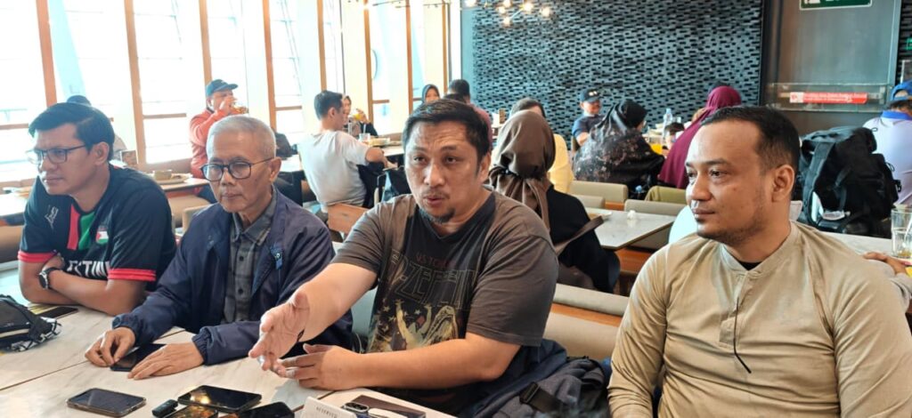 whatsapp image 20260419 at 184752 dompet dhuafa Four men sit at a long restaurant table; the man in the center speaks and gestures with his hand as others listen.