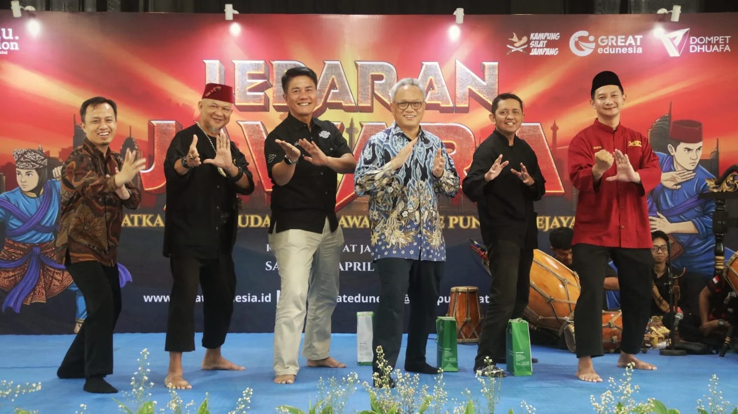 whatsapp image 20260427 at 141124 dompet dhuafa Group of six men on a stage posing in martial-arts stances in front of a colorful event banner. Note: The banner includes large letters and logos in the background.