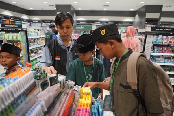 50anakyatimbelanjagramediabsd05 dompet dhuafa Adult guides three boys as they browse a colorful stationery display in a store aisle.