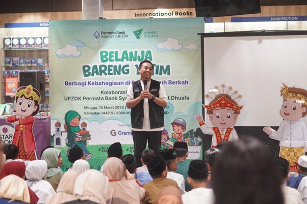 50anakyatimbelanjagramediabsd08 dompet dhuafa Speaker on stage at a charitable event banner reading 'Belanja Bareng Yatim', with audience of families and children in a store setting during Ramadan.