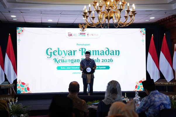 dampakzakatroisojkdandompetdhuafa20265 dompet dhuafa Speaker on stage delivering a talk at a Ramadan event; large banner reads 'Gebyar Ramadan Keuangan Syariah 2026' with Indonesian flags on both sides.