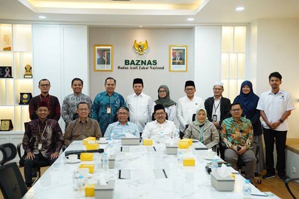 Group photo of a diverse team in a conference room at BAZNAS, posing for a formal meeting in front of the organization’s logo and portraits on the wall.