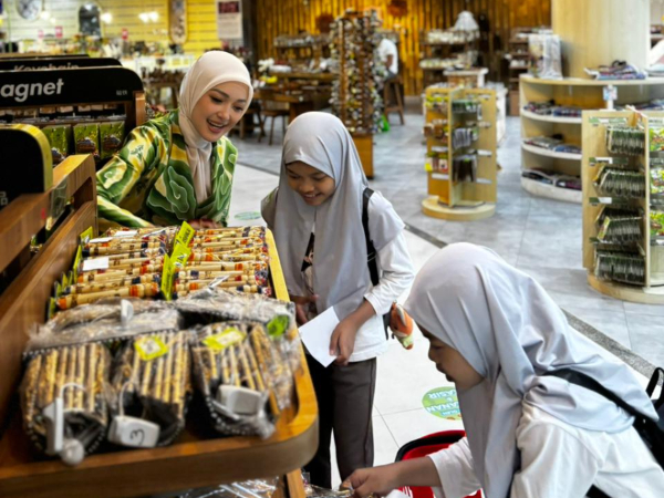 fotojet1 1 dompet dhuafa Three girls wearing hijabs browse a snack display in a bright grocery store.