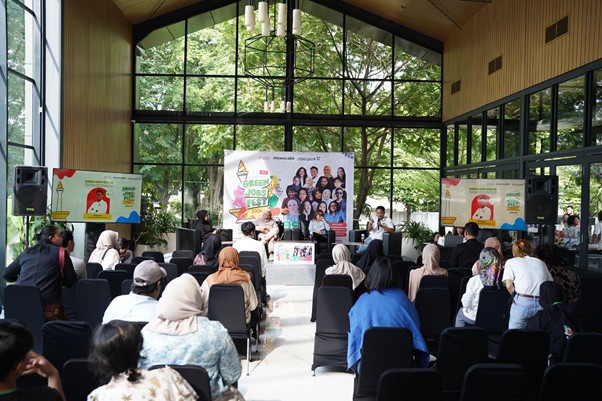 greenjobsdanekonomihijau4 dompet dhuafa Audience seated in a bright hall watching a stage performance at Green Fest with banners and a large central poster behind the performers.