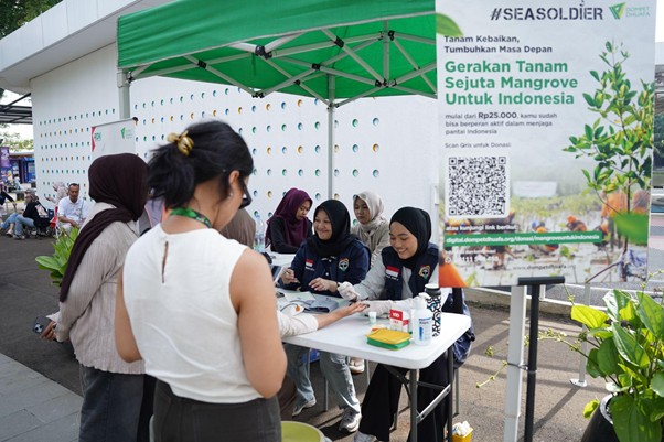 greenjobsdanekonomihijau6 dompet dhuafa Group of women at a registration table under a green canopy, participating in a mangrove conservation donation campaign.