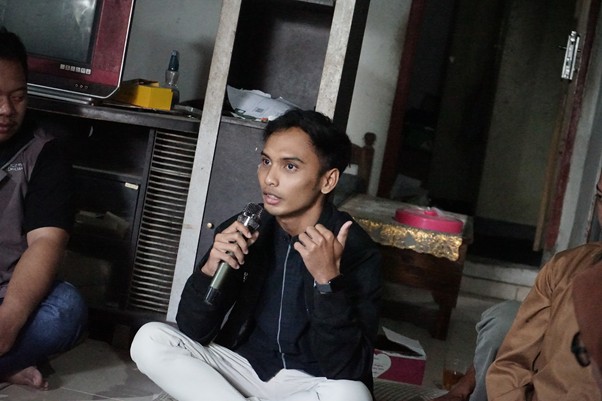 jantarakabul4 dompet dhuafa Young man sitting on the floor, speaking into a handheld microphone during a casual discussion indoors.