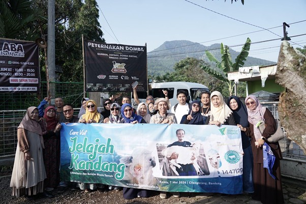 jelajahkandanguntukkurban202616 dompet dhuafa Group of people posing outdoors, holding a blue banner that says 'Jelajah Kandang' for a community event, with buildings and mountains in the background.