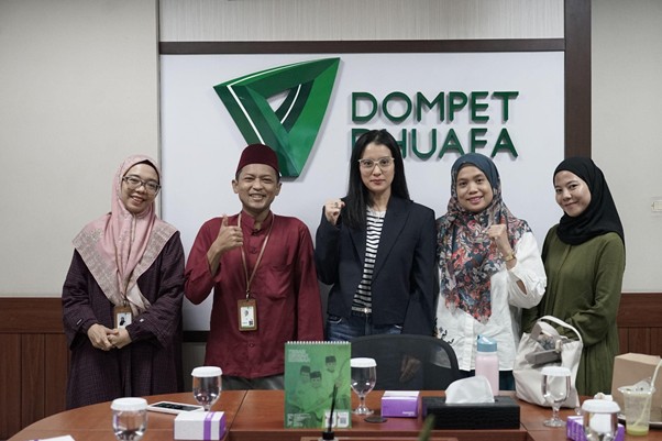 kolaborasi marcella zalianty 1 dompet dhuafa Group of five people posing for a photo in a conference room, with a Dompet Dhuafa sign in the background and thumbs up gestures.