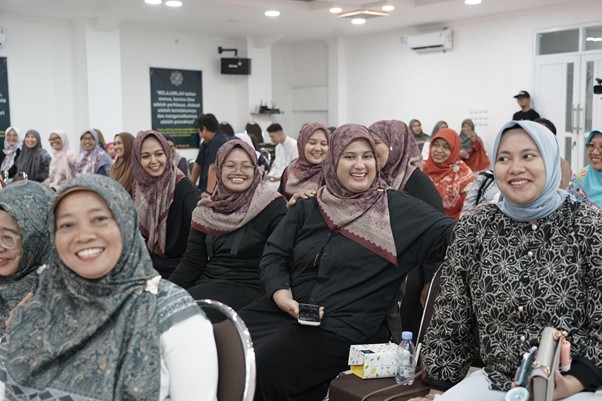 Group of women wearing hijabs seated in a bright conference room, smiling during a seminar or workshop.