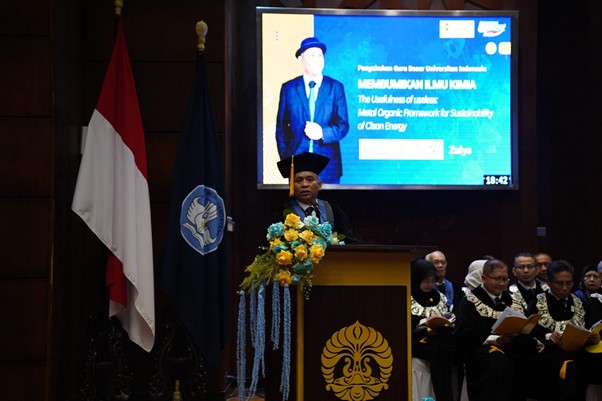 pelantikanagustinozulys3 dompet dhuafa A man in a suit and hat speaks at a flower‑decorated podium during a formal ceremony, with flags and a large screen in the background.