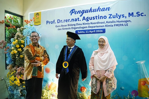 pelantikanagustinozulys8 dompet dhuafa Stage with a blue banner for an induction ceremony; a batik-clad man shakes hands with a graduate in a cap and gown while a woman in a pink hijab smiles nearby.