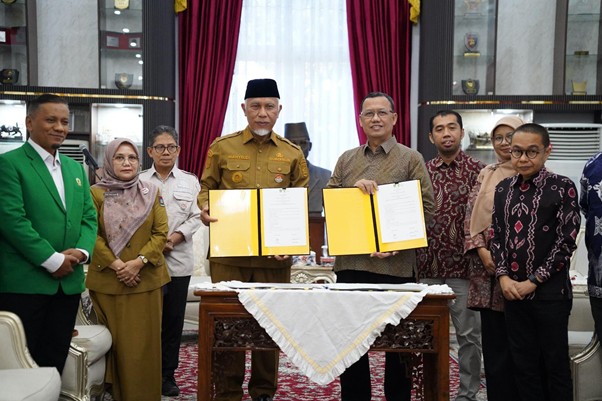 pemprov sumatera barat 1 dompet dhuafa Group of people at a signing ceremony; two men in the center hold open yellow folders with signed documents, red curtains in the background.