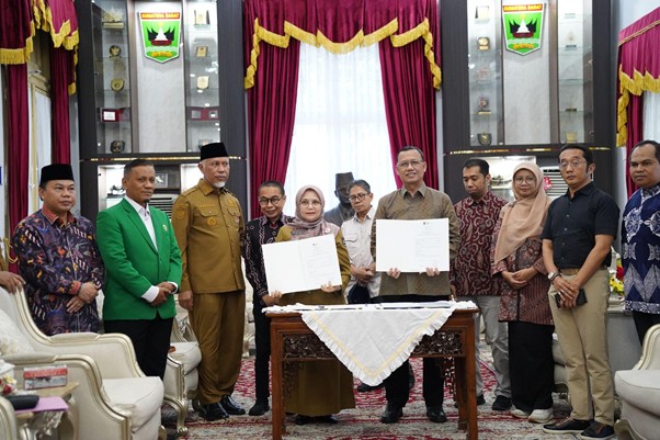 pemprovsumaterabarat6 dompet dhuafa Group of officials and civilians at a formal signing ceremony; two people hold documents on a table while others look on.