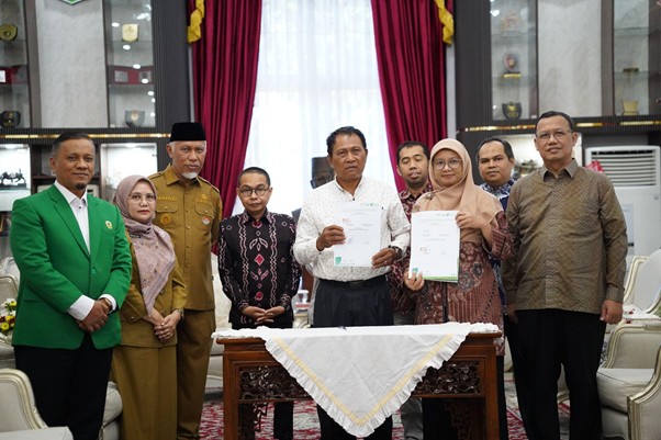 pemprovsumaterabarat8 dompet dhuafa Eight adults stand behind a carved table in a formal room; two in the center hold signed documents during a ceremony.