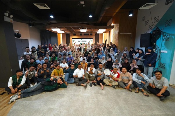 Large group of diverse people posing together in a bright, modern event space for a group photo. Everyone is smiling and arranged in several rows.