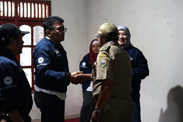 press touring kurban 1447 h 2 dompet dhuafa Police officer in tan uniform shakes hands with a man in a dark blue jacket while others watch indoors.