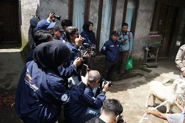 press touring kurban 1447 h 5 dompet dhuafa A group of photographers and reporters outside a weathered building, taking photos of a sheep tied near the entrance.