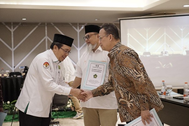 sklaz20264 dompet dhuafa Three men in a ceremony shake hands; one recipient holds a framed certificate while others look on in a conference room.
