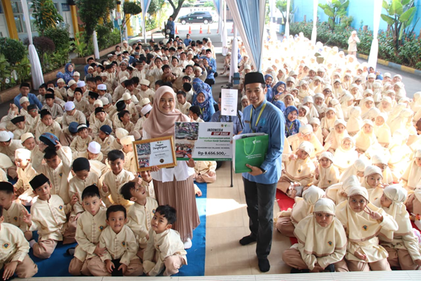 sumaterabangkit2 dompet dhuafa Large outdoor ceremony with hundreds of students in beige uniforms; two adults present a framed certificate and a donation check to the group.