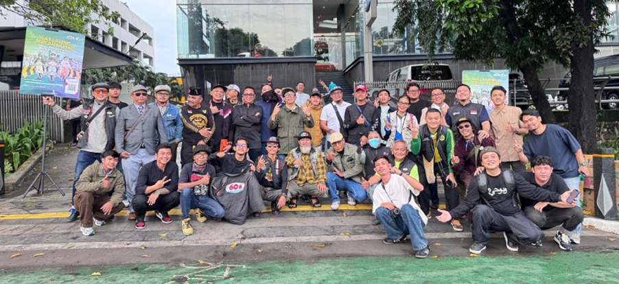 vespa60sjabodetabekdanscomadiindonesia5 dompet dhuafa Large group of people posing for a group photo on a sidewalk in front of a modern glass building with banners nearby.