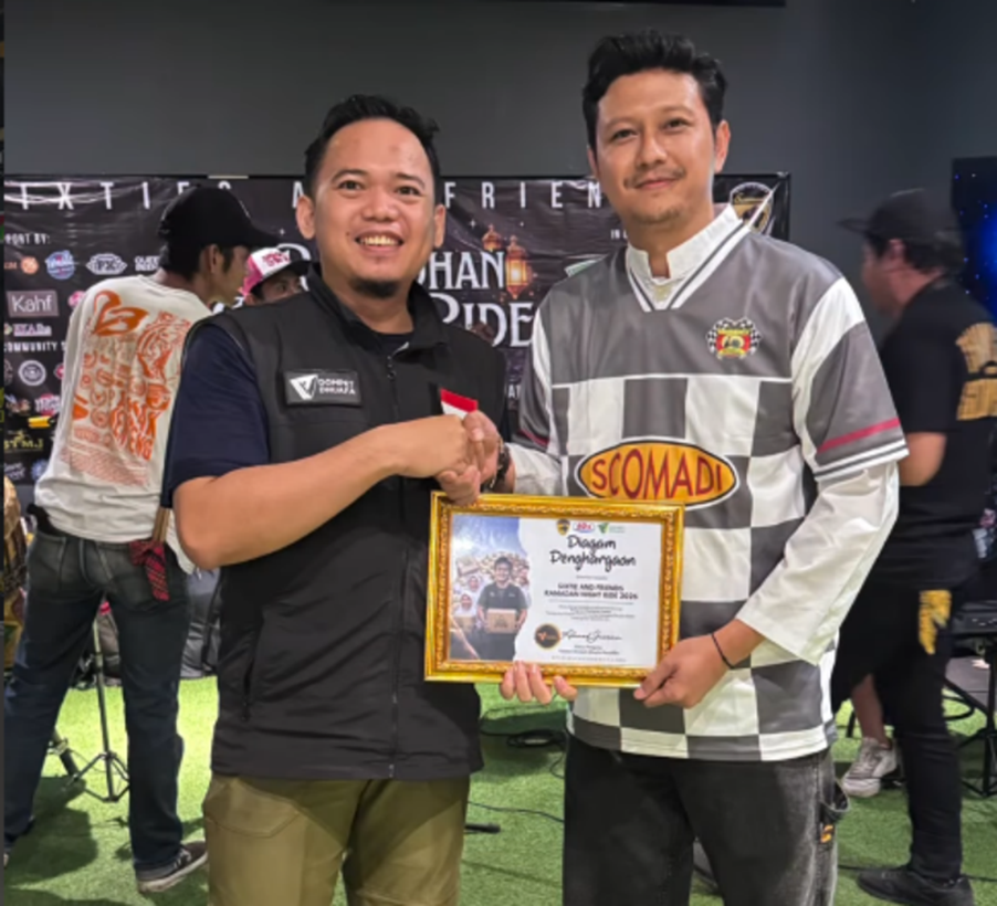 vespa60sjabodetabekdanscomadiindonesia6 dompet dhuafa Two men smile and shake hands while one holds a framed certificate at an awards event in a crowded venue.