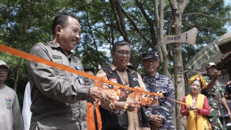 Officials cut an orange ribbon at an outdoor ceremony, surrounded by uniformed personnel and a woman in traditional attire.