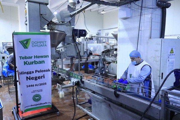 kurban di palestina 5 dompet dhuafa Meat processing facility with a conveyor line; worker in PPE (blue cap and mask) at the machine; banner reads 'Dompet Dhuafa Tebar Hewan Kurban Hingga Pelosok Negeri 1446 H/2025'.