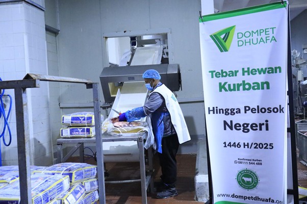 kurban di palestina 7 dompet dhuafa Worker wearing a mask and gloves packages meat on a processing table, with a Dompet Dhuafa Kurban banner in the background.