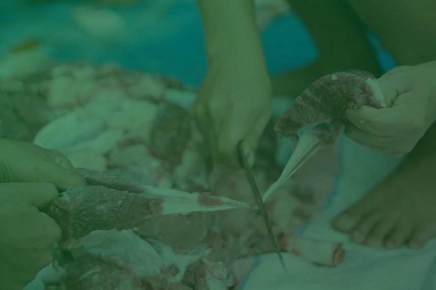 lebaran idul adha berkah dompet dhuafa People cutting raw meat on a board, using knives to portion and trim bone-in pieces. Readable, concise description of the scene for context and purpose as an informative image.