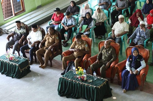 nusadayantt2 dompet dhuafa Front-row officials in uniform and traditional attire sit at a formal ceremony, with audience seated behind them in a hall.