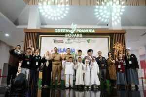 belanja bareng yatim green pramuka 1 dompet dhuafa Group of children and adults posing on a stage at Green Pramuka Square during a community event, with banners and decorative lights in the background.