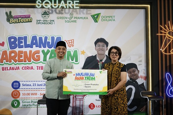 Group of four people on a stage holding a colorful banner at an event, smiling for the camera.