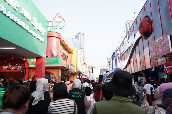 belanja bareng yatim prj 2026 2 dompet dhuafa Busy outdoor shopping street with colorful storefronts and a crowd of people seen from behind.
